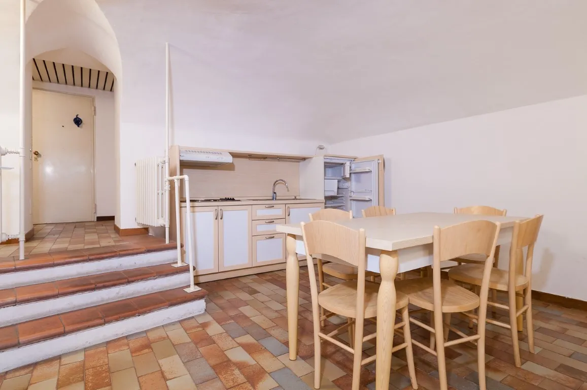 Cocina con mesa de comedor, techo abovedado y escalera hacia la entrada