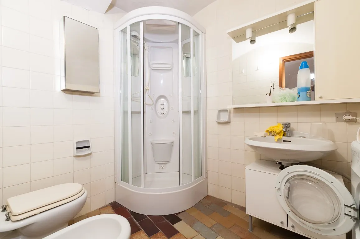 Baño con cabina de ducha de hidromasaje, bidé y lavadora