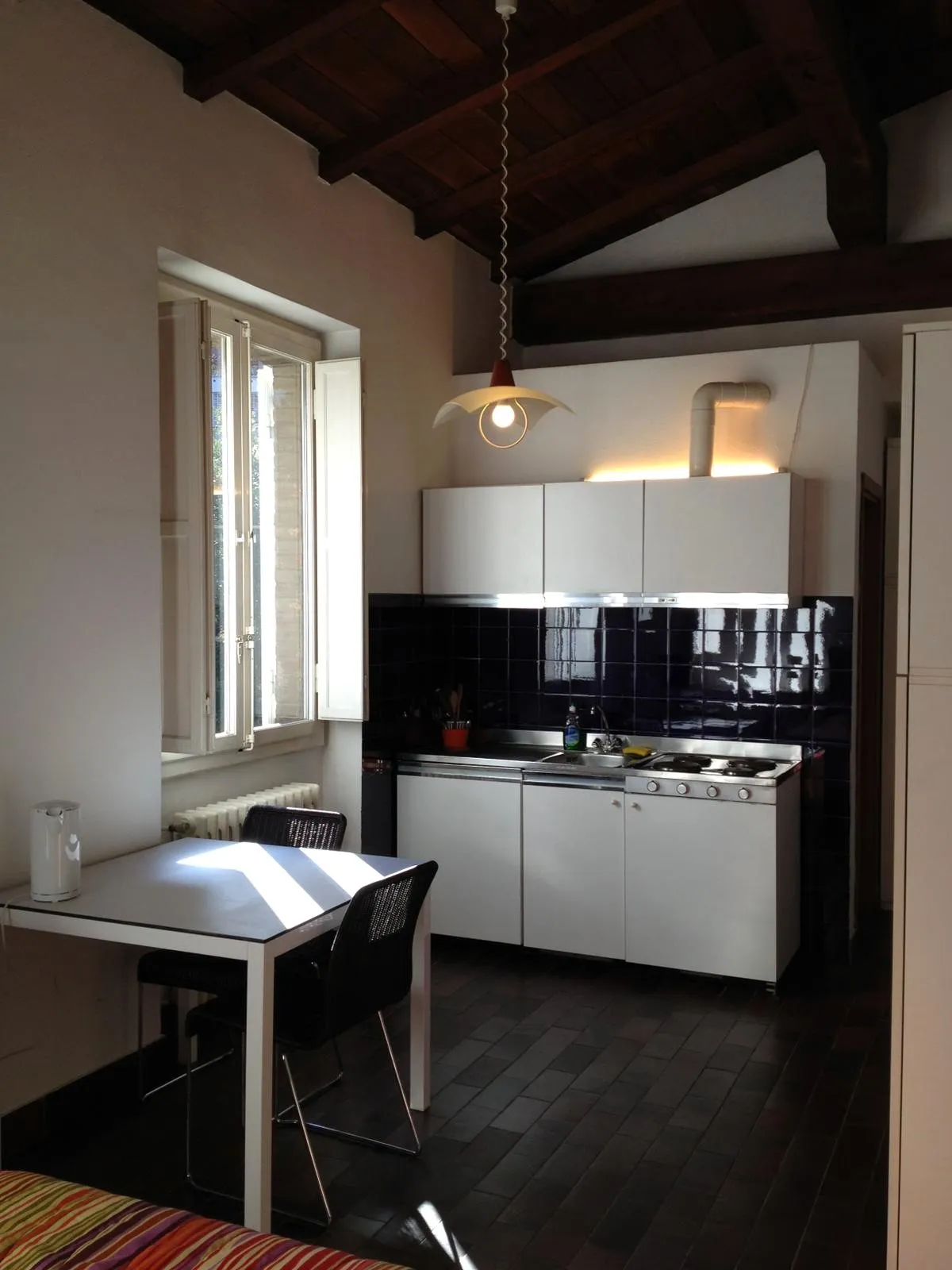 Cocina americana con vigas de madera vistas y mesa junto a la ventana