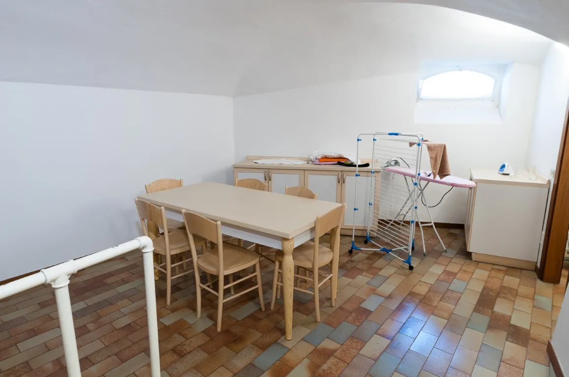 Zona de comedor en la planta inferior con mesa, aparador y ventana de medio punto