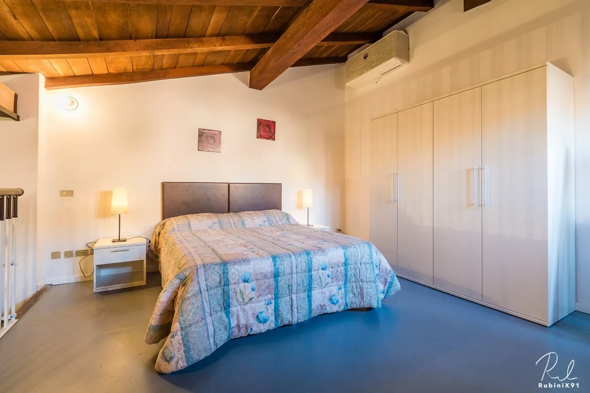 Dormitorio en el altillo con armario y vigas de madera vistas
