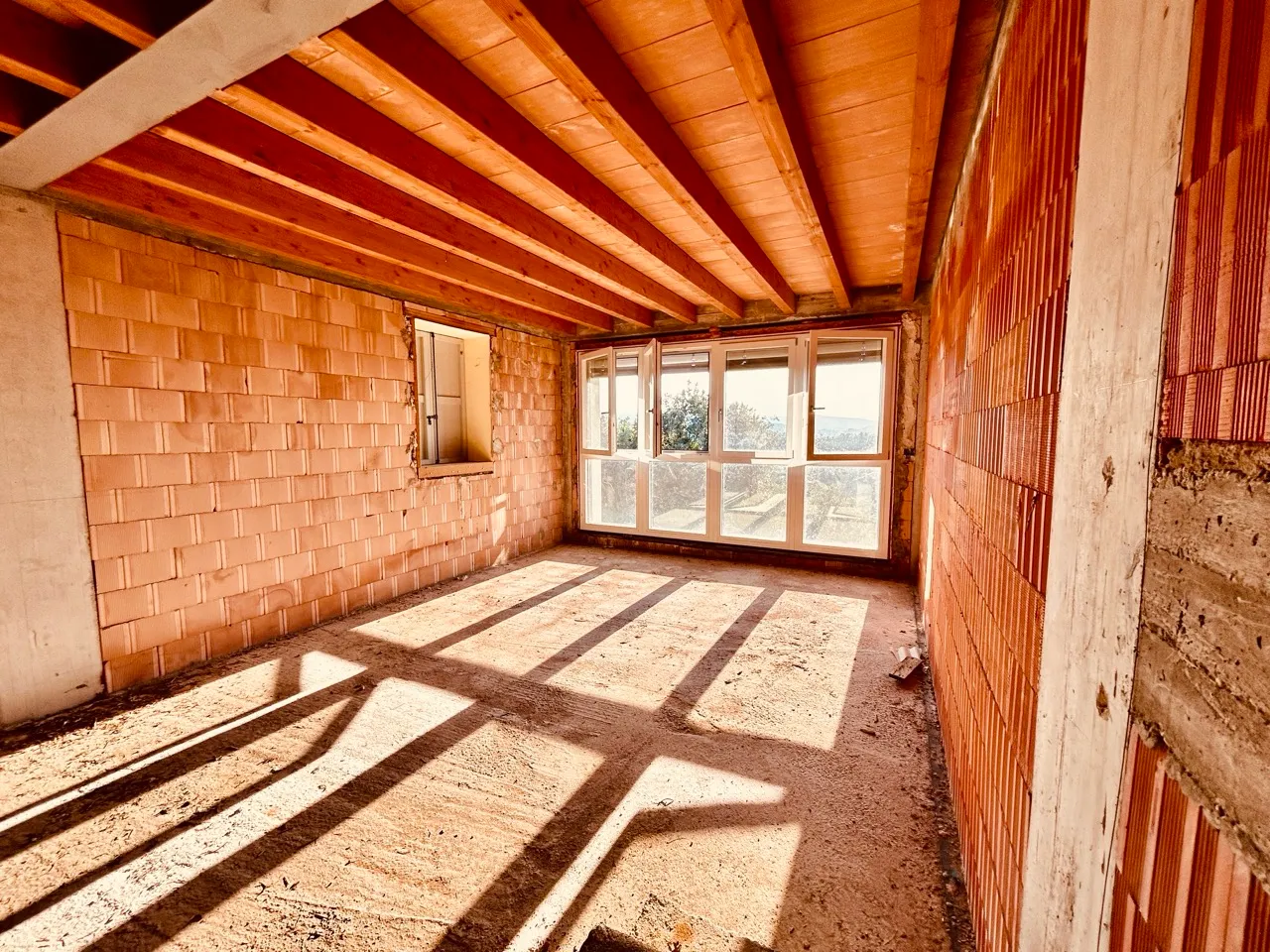 Interno al grezzo con soffitto in legno e ampie finestre panoramiche