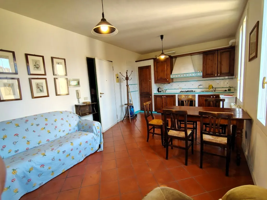 Zona giorno con angolo cottura, divano e tavolo da pranzo