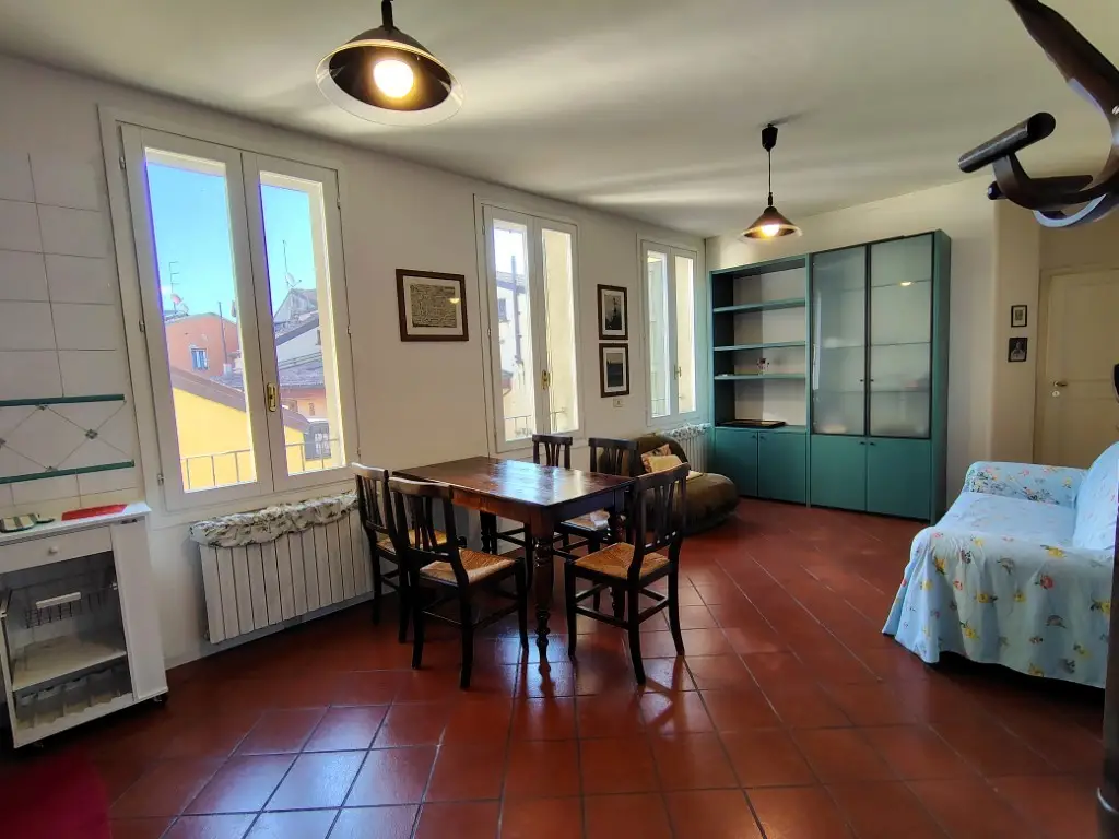 Soggiorno luminoso con tavolo da pranzo, libreria e finestre sui tetti del centro