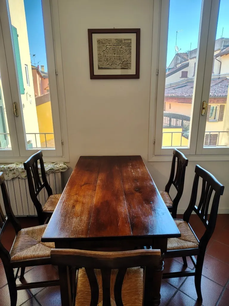 Tavolo da pranzo fra due finestre ad angolo, con vista sui tetti del centro storico